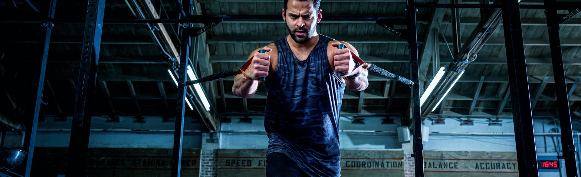 A man in a gym exercising with some pull weights.